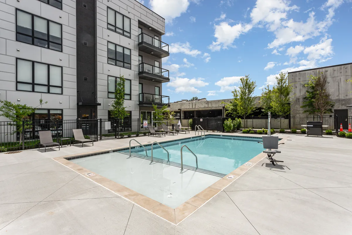 A resort-style swimming pool with lounge chairs, balconies, and landscaped surroundings invites guests to unwind or socialize outdoors. The image evokes a sense of leisure and escape between work commitments.