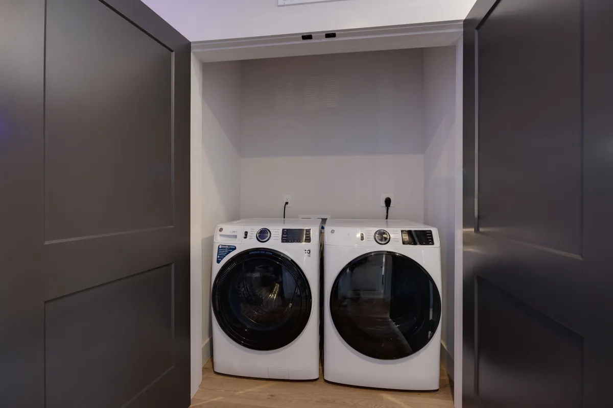 This practical image displays a modern washing machine and dryer set within a bright, clean laundry area. The streamlined appliances promise convenience and ease for extended stays or families needing in-unit laundry.